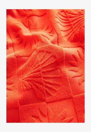 Oranger strukturierter Stoff mit erhabenen Mustern von Muscheln und abstrakten Formen, der eine taktile und gemusterte Oberfläche schafft.