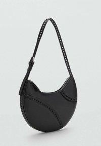 Black faux leather shoulder bag with a curved shape, decorative cutouts along the seams, and an adjustable strap. Zipper closure on top.