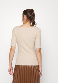 Beige getailleerde top met korte mouwen en een brede ronde halslijn, gecombineerd met een geplooide bruine rok. Gladde textuur, eenvoudig ontwerp.