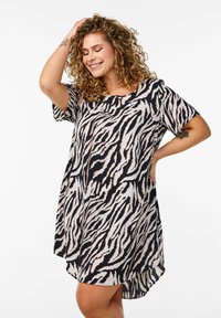 Robe à manches courtes en imprimé zèbre noir et blanc, avec une coupe ample et un ourlet arrière plus long, réalisée en tissu doux et léger.