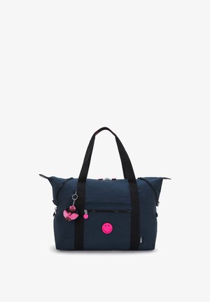 Marineblå tote-taske med sorte håndtag, frontlomme med lynlås og lyserødt smiley-patches samt nøglering med en bamse i tutu.