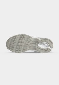Η σόλα ενός αθλητικού παπουτσιού New Balance σε ανοιχτό γκρι χρώμα με υφή πέλματος και ορατό λογότυπο της μάρκας στο κέντρο.