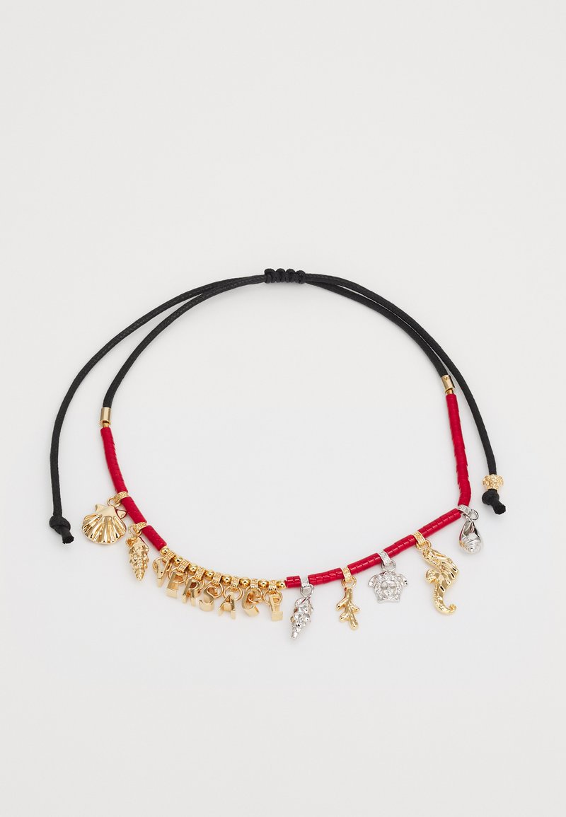 Collar de encantos dorado con cordón rojo y negro. Presenta varios encantos, incluyendo una concha, una uva, un caballito de mar y la inscripción "VERSACE".