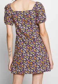Kwiatowa sukienka z kwadratowym dekoltem, krótkimi bufkami i dopasowanym gorsetem, z fioletowym tłem i kolorowymi wzorami kwiatowymi.