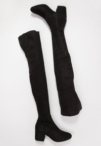 Czarne kozaki za kolano wykonane z miękkiego zamszu, na grubym obcasie. Posiadają boczny zamek błyskawiczny oraz gładką fakturę z zaokrąglonym noskiem.