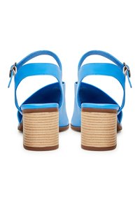 Blå läderblockklackssandaler med korsade remmar, justerbar ankle buckle och slät textur; klack med träfinish och ribbad detalj.