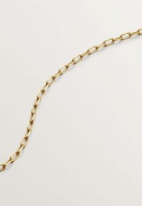 Collar de cadena de oro con eslabones ovalados alargados, textura suave, acabado brillante, colocado sobre un fondo claro.