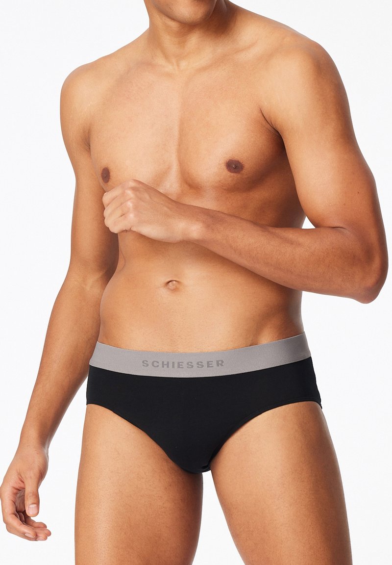 Culotte noire en coton avec une ceinture grise arborant le logo "Schiesser". Le design est simple et ajusté, mettant en avant un style classique.