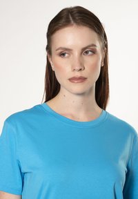 Lichtblauwe katoenen T-shirt met korte mouwen, ronde hals en een gladde textuur. Het shirt heeft minimale stiksels en een klassieke pasvorm.