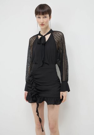 Schwarzes Kleid mit taillierter Passform, langen Spitzenärmeln, gebundenem Ausschnitt und Rüschensaum, aus strukturiertem Stoff und mit drapierter Gestaltung.