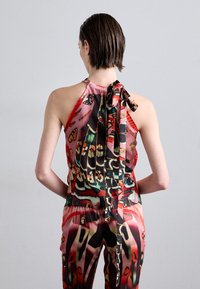 Musteroberteil mit Halterneck und Bindeband am Rücken, mit lebendigen Farben, Blumenmotiven und einer glatten, seidigen Textur.