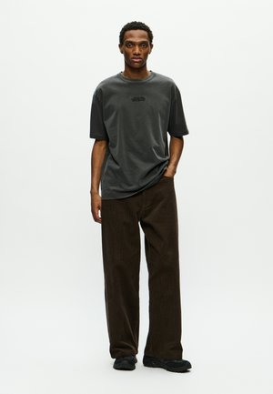 Gray cotton t-shirt with short sleeves and a crew neck, paired with brown corduroy pants featuring a textured vertical pattern.