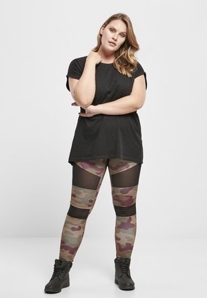 Black t-shirt, camouflage leggings featuring mesh panels, and black ankle boots. The leggings display shades of green, brown, and burgundy.