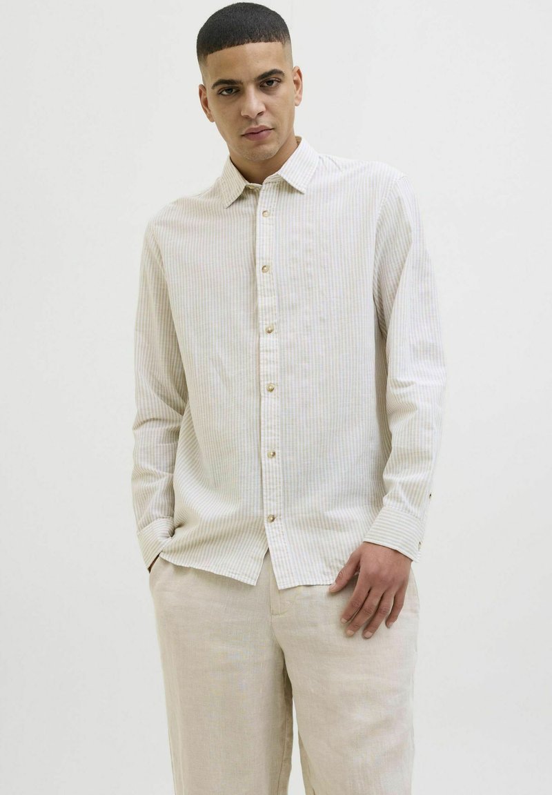 Camisa de botones a rayas claras en beige y colores pastel. Presenta un cuello clásico y botones dorados, fabricada con un tejido suave y texturizado.