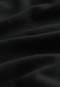 Black fabric with a soft texture, featuring subtle waves and folds. The material appears lightweight and smooth.