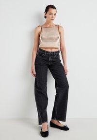 Stribet strik crop top i beige og brun, parret med højtaljede sorte denim jeans. Sorte balletflade fuldender looket.