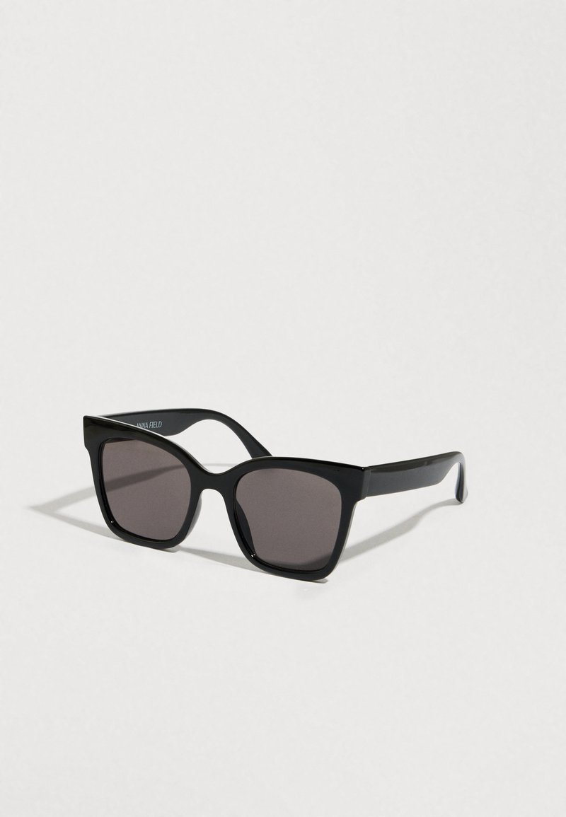 Lunettes de soleil noires avec une monture en plastique solide. Verres carrés avec un dégradé de teinte. Texture lisse et branches légèrement courbées pour un ajustement sécurisé.