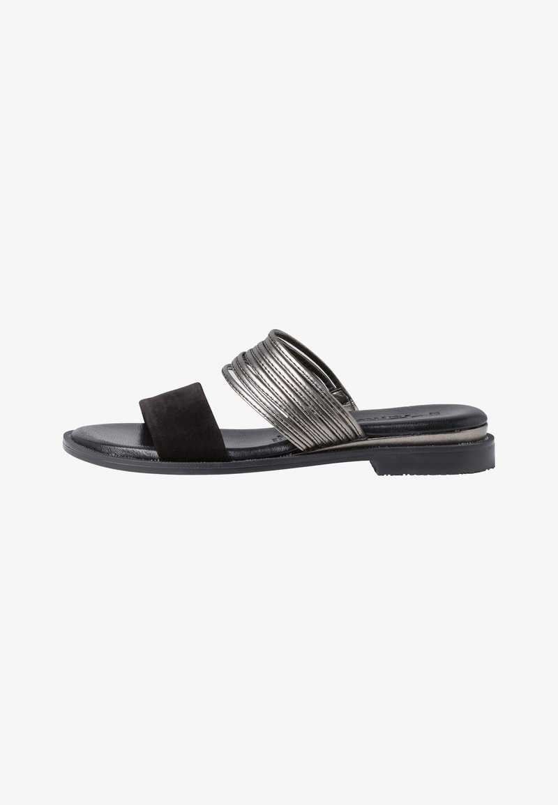 Sandale plate noire avec deux brides, une en daim noir et une métallisée texturée, avec un petit talon sur fond blanc.