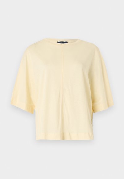Haut à manches courtes et coupe décontractée en tissu jaune clair doux. Présente un col rond simple et une couture centrale pour plus de détails.