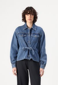 Veste en denim avec une taille ceinturée, deux poches poitrine, fermeture à boutons sur le devant et manches longues. Couleur bleu clair à moyen avec une coupe décontractée.
