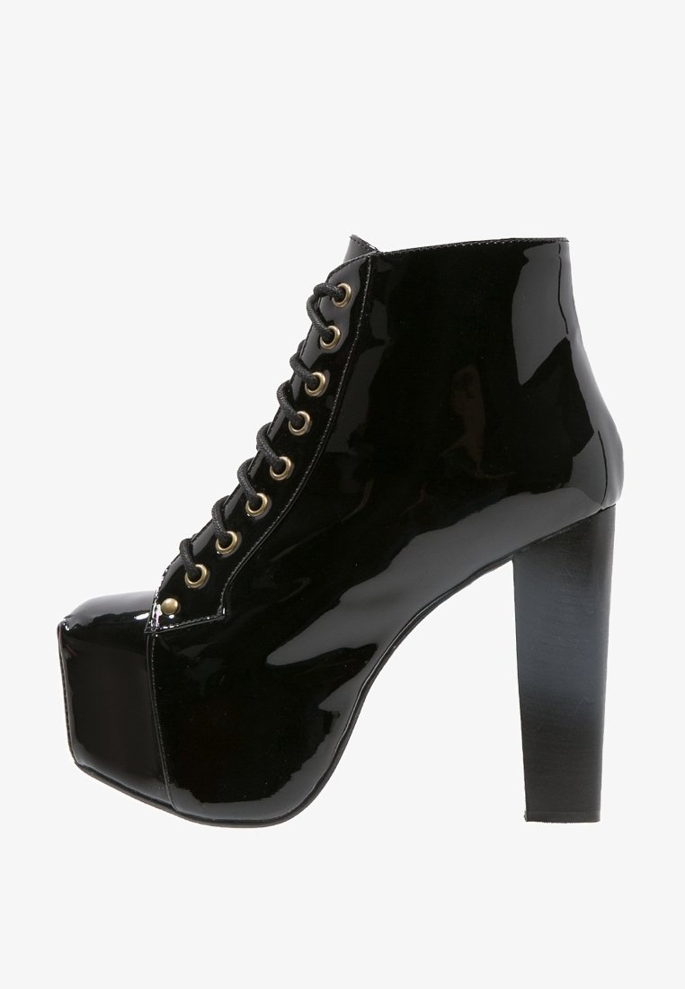 Zwarte patenten leren platform enkellaars met een chunky hoge hak en vetersluiting, versierd met gouden oogjes.