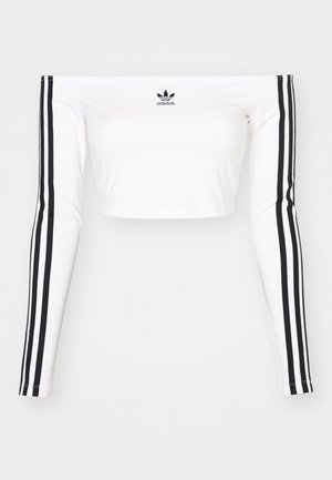 Weißes langärmeliges Off-Shoulder-Crop-Top aus dehnbarem Material. Mit schwarzen drei-Streifen-Akzenten an den Ärmeln und einem kleinen schwarzen Logo auf der Brust.