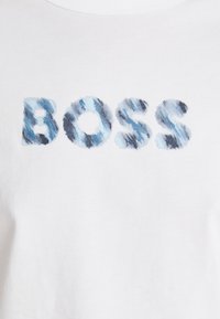 Balta medvilninė marškinėliai su žodžiu „BOSS“ mėlyno gradientu, raidėse su tekstūruotu, šepečiu apdirbtu raštu.