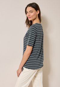 Camiseta de rayas gris oscuro con mangas cortas, cuello redondo, con rayas horizontales blancas y un corte holgado. Textura de tela suave.