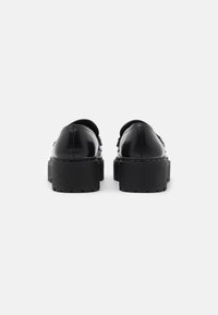 Scarpe platform in pelle nera con finitura liscia, punta arrotondata e suola testurizzata, caratterizzate da un design senza tallone e senza hardware visibile.