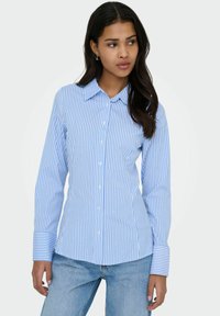 Chemise à rayures bleu clair et blanches à boutons, manches longues, col et poignets retroussés. Fabriquée en tissu lisse, avec une coupe ajustée.