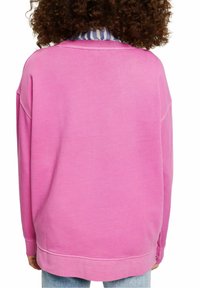 Felpa rosa oversize con colletto rotondo e polsini a coste, realizzata in tessuto morbido. Caratterizzata da un orlo dritto e un taglio casual.