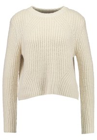 Grob gestrickter cremefarbener Pullover mit rundem Ausschnitt und langen Ärmeln. Strukturierte Musterung mit dezenten diagonalen Designdetails vorne.