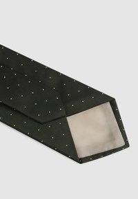 Crna leptir mašna s bijelim točkicama, teksturirana tkanina, šiljati kraj i glatka unutarnja podstava. Uzorak ravnomjerno raspoređen.