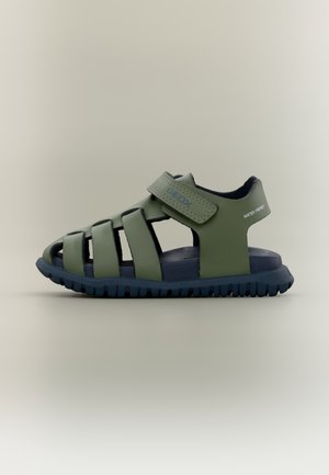 Sandalia verde con diseño transpirable, con tiras anchas y cierre de velcro. Suela de goma con superficie texturizada para mayor agarre. Resistente al agua.