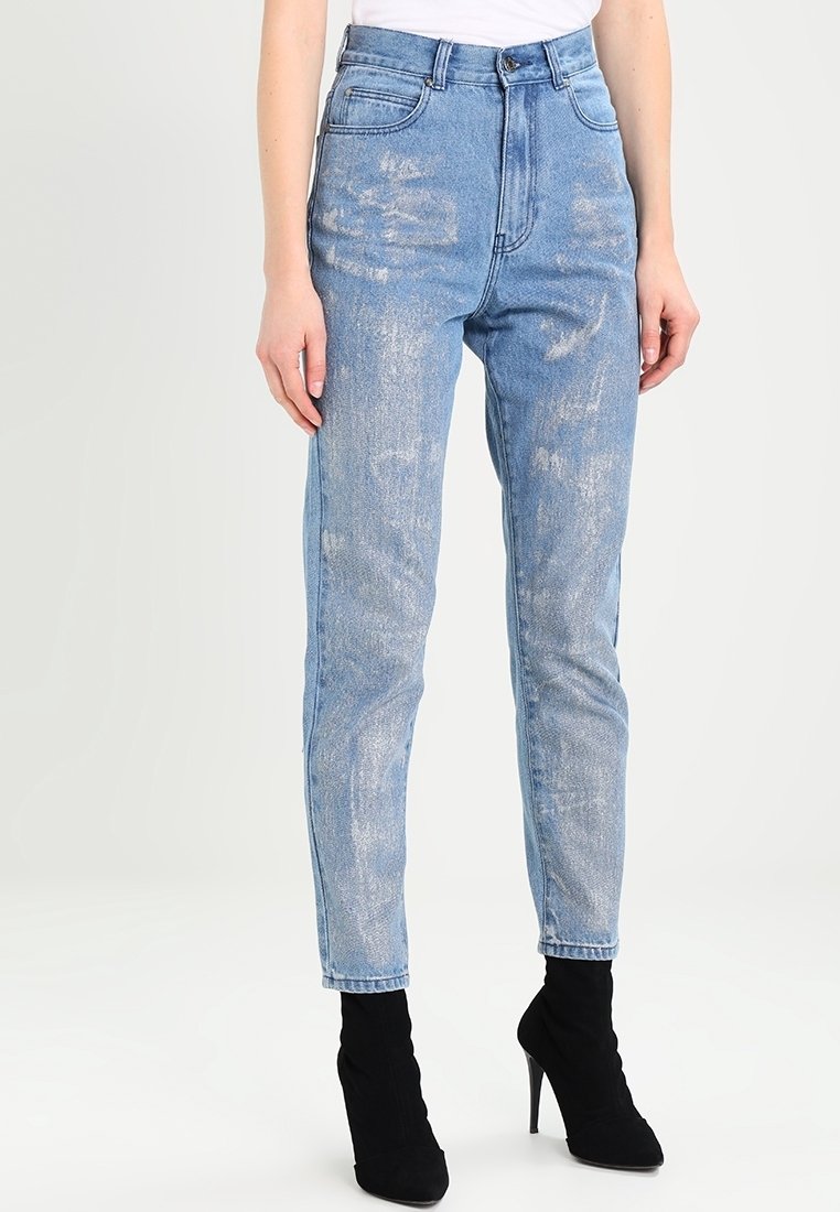 Světle modré džínové kalhoty s vysokým pasem, tapered nohavicí a poškozenými detaily. Mají pět kapes a zapínání na knoflík.