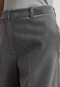 Szare spodnie bawełniane z domieszką, o gładkiej teksturze, z dopasowanym krojem, prostym przodem i dwoma bocznymi kieszeniami. Widoczne subtelne detale w stębnowaniu.