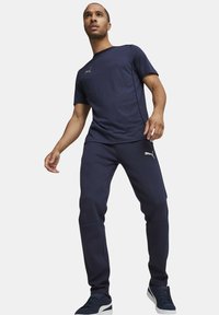 Marinblått idrottsset bestående av en kortärmad T-shirt och tapered byxor. Tyget är slätt med kontrasterande logotyp och sömnadsdetaljer.
