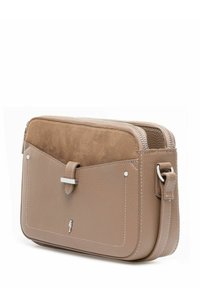 Beżowa skórzana torebka na ramię z zamszową kieszonką z przodu, srebrnym zapięciem i regulowanym paskiem, prezentowana na białym tle.