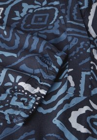 Marinfärgad tyg med abstrakta blå och vita mönster. Slät textur, har intrikata designer med former och linjer. Rundade kanter synliga.