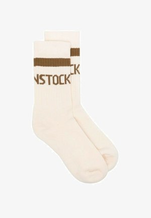 Calzini beige con risvolti a costine marroni e testo intrecciato che legge "BIRKENSTOCK". Texture liscia, lunghezza fino al polpaccio, design casual.