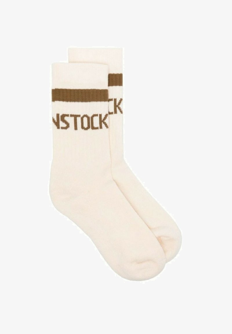 Calzini beige con risvolti a costine marroni e testo intrecciato che legge "BIRKENSTOCK". Texture liscia, lunghezza fino al polpaccio, design casual.