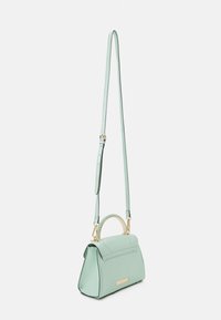 Mintgrön handväska med en strukturerad design, locköppning och guldfärgad hardware. Utrustad med ett avtagbart rem och ett litet handtag upptill.
