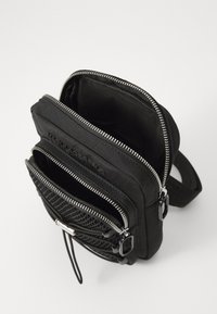 Borsa a tracolla nera con molteplici scomparti con zip, finitura in tessuto liscio, hardware in argento e un accento a motivo testurizzato.