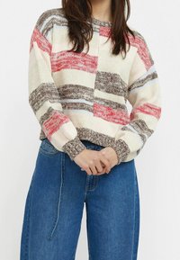 Maglione lavorato a maglia con colletto tondo, caratterizzato da strisce rosse, marroni e blu su uno sfondo avorio. Vestibilità morbida con polsini e orlo a coste.