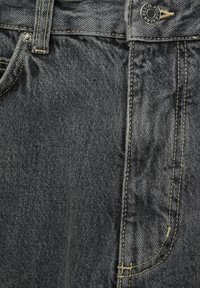 Jean en denim gris foncé avec des coutures jaunes contrastantes, doté d'une poche avant et d'un bouton en métal. Texture lisse avec des variations subtiles.