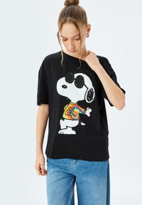 Zwarte katoenen t-shirt met een graphic van Snoopy in een zonnebril en een kleurrijk shirt met "JOE COOL". Korte mouwen en een ontspannen pasvorm.