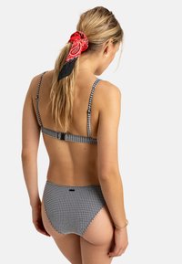 Bikini set v čierno-bielej kárované vzore s nastaviteľnými ramienkami a zapínaním na sponu, s vysokým strihom na nohách a minimalistickým dizajnom.