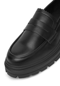 Loafers din piele neagră, cu o talpă robustă, un vârf rotunjit neted și o bandă decorativă cu accente în zigzag.