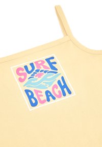 Camiseta sin mangas amarilla con un gráfico cuadrado que presenta el texto "SURF BEACH" en rosa y azul, junto con ilustraciones de olas y el sol. Material de algodón suave.