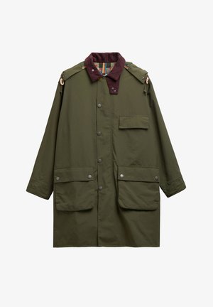 Μακρύ παλτό σε ελιά πράσινο με γιακά από καφέ σκοτεινό κοτλέ, κουμπιά με τρουκς εμπρός, δύο μεγάλες τσέπες με καπάκι, μία τσέπη στο στήθος και λουριά στους ώμους.